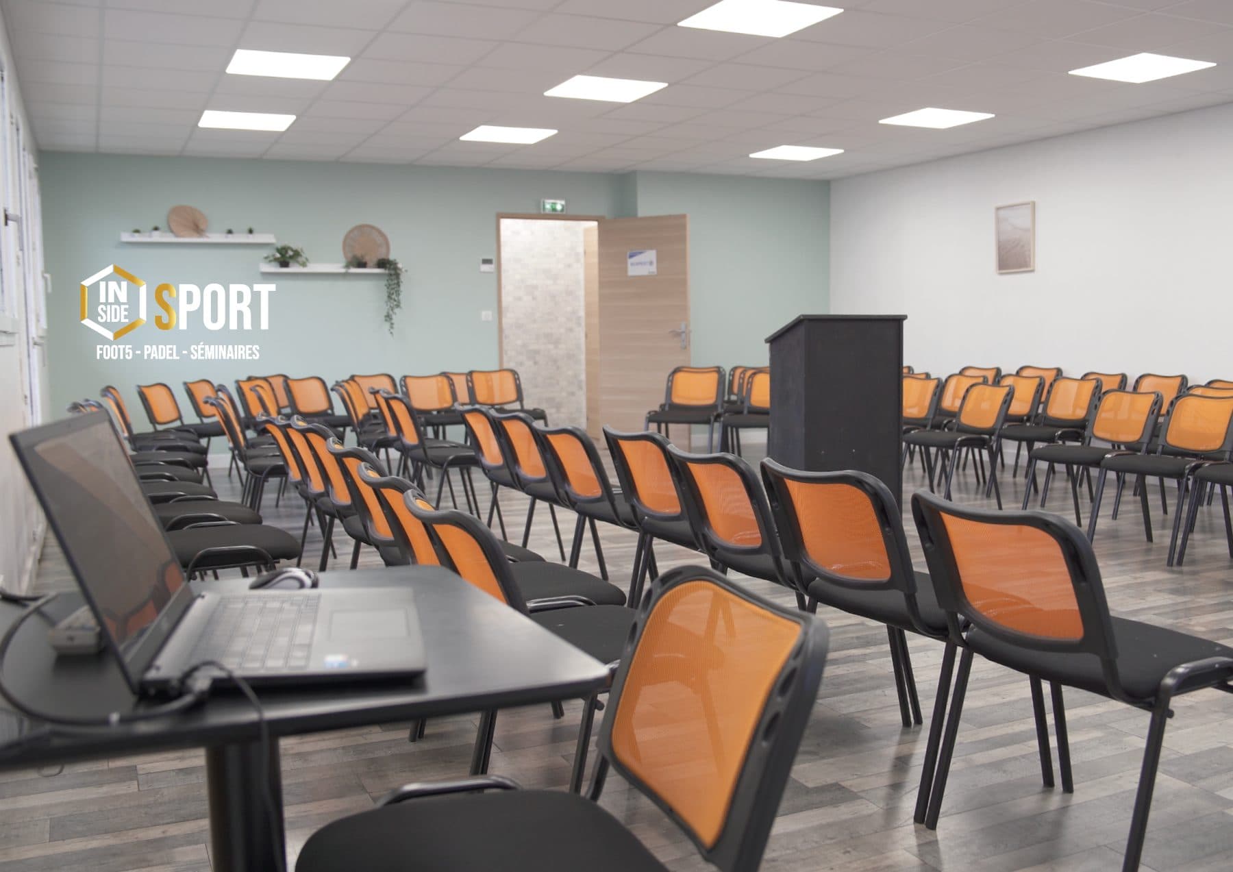 Salle en configuration conférence avec pupitre et ordinateur