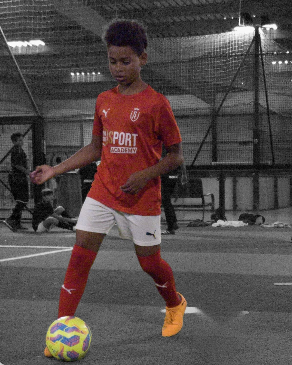 Jeune joueur de l'Inside Academy en maillot du Stade de Reims, ballon au pied