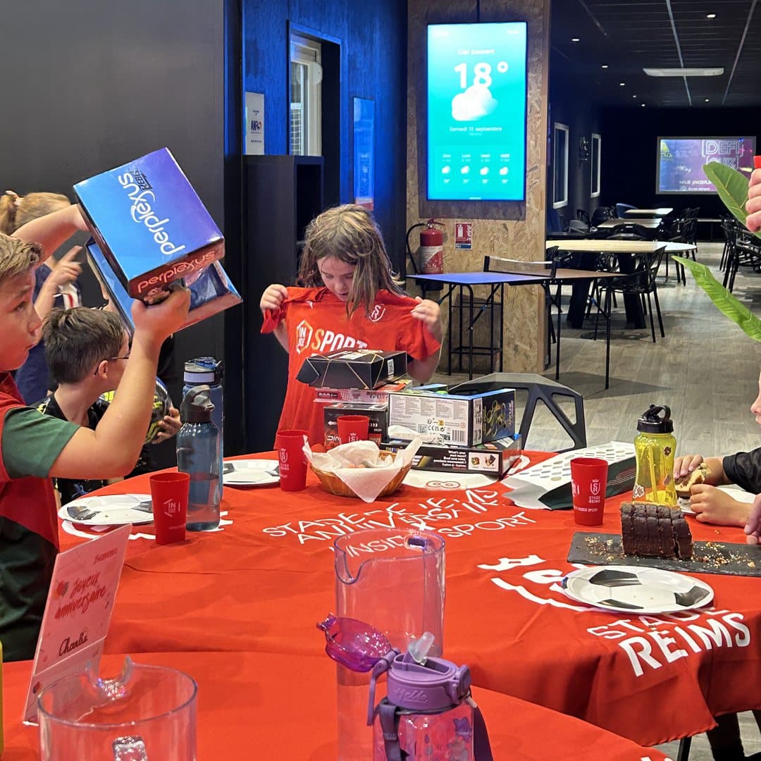 Ouverture des cadeaux autour de la table d'anniversaire aux couleurs du Stade de Reims