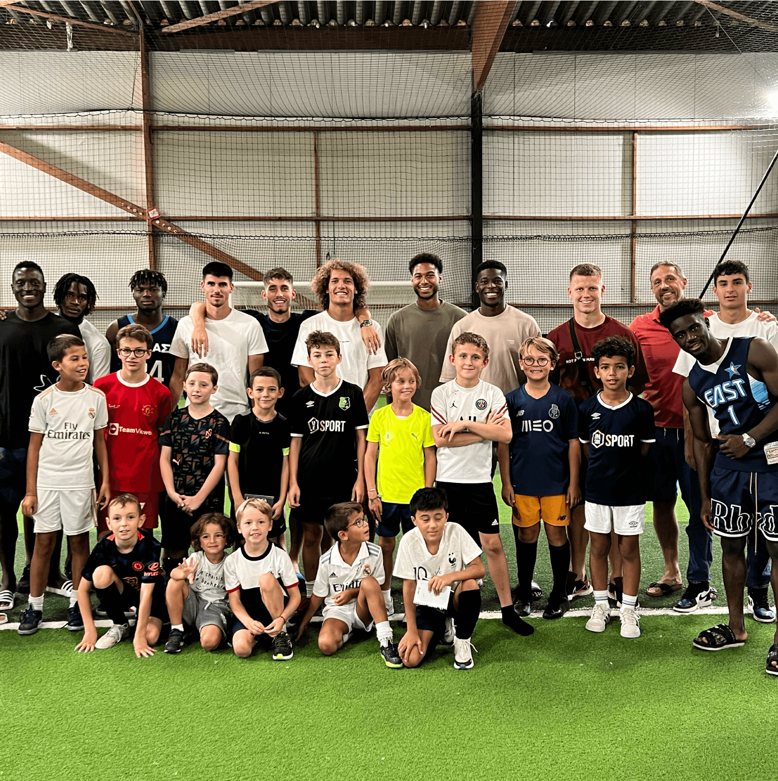 Joueurs professionnels posant avec les enfants du stage sur le terrain
